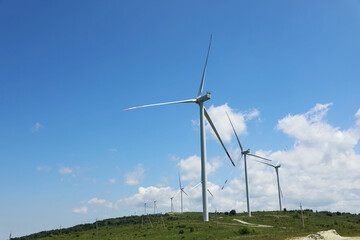 Modern wind turbines in field on sunny day. Space for text