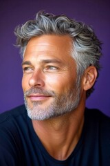 Obraz premium Modish men's layered waves haircut - midlife white man with grey hair. Purple solid background. Conceptual art pattern of style for aging men. A confident and modern man embracing his look.