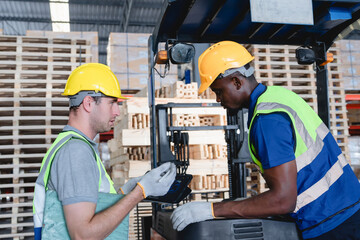 Two warehouse workers examining forklift components during routine maintenance in industrial...