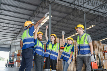 Diverse group of warehouse workers celebrating teamwork success with high five in storage facility, Teamwork celebration concept.