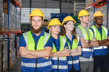 Confident multicultural warehouse team standing in line with arms crossed, representing teamwork,...