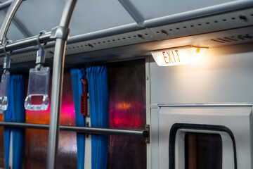 The emergency exit sign inside of bus or train with curtains and window.