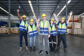 Group of happy industrial workers cheering and raising fists in unity after completing a project...