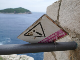 Attention sign in multiple languages blown upside down with wind