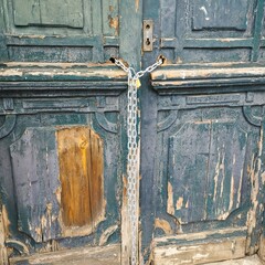 A door with a chain and lock on it. The door is old and has a lot of wear and tearA door with a chain and lock on it. The door is old and has a lot of wear and tear