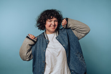 Smiling person in casual denim jacket against blue background.