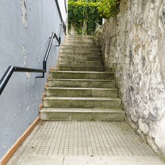 A stone staircase leading up to a building. The steps are worn and dirty, and the handrails are...