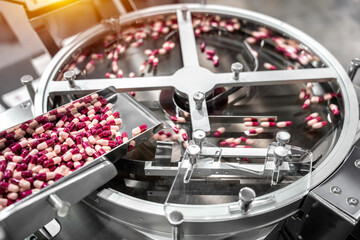 Pink and white capsules pills in the pills packaging machine, pharmacy medicine capsule pill in...