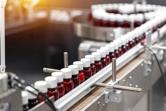 Sterile bottles on the production line conveyor of the pharmaceutical industry. Machine for liquid drugs glassware bottling. - Powered by Adobe