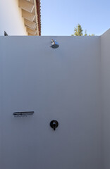 outdoor shower in hotel room in antigua guatemala latin america (luxury travel outside bathing bath head faucet soap holder knob) metal white wall hot climate minimalist photo
