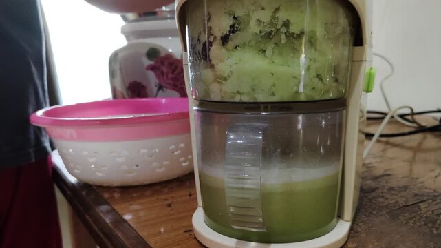 Someone placing slices of fresh bottle gourd or calabash gourd into a juicer to prepare a healthy drink at home.