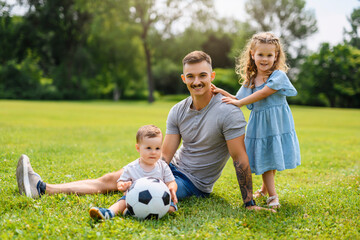 Fototapeta premium Young father with his little son and daughter playing soccer