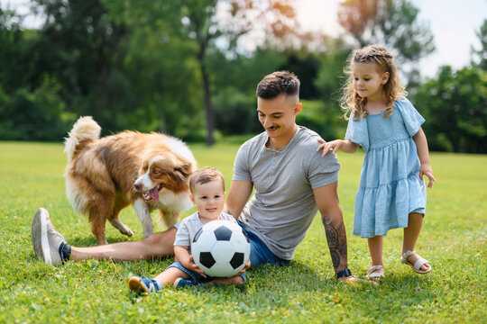 Young father with his little son and daughter playing soccer