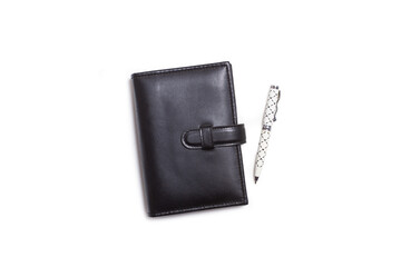 A black diary and a pen on a white background with copy space
