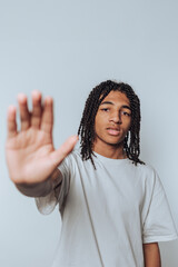 Young man with dreadlocks making a stop gesture with his hand.