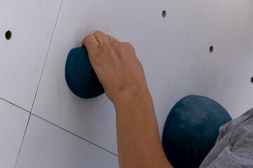 Child climbing artificial rock wall using colorful handhold