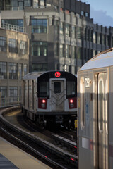 train arriving on platform in court square queens long island city new york nyc famous outdoor elevated station stop seven 7 metro commuter line tall buildings in background tracks railroad track