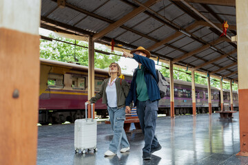 Fototapeta premium Happy Asian senior boarding a train at the station