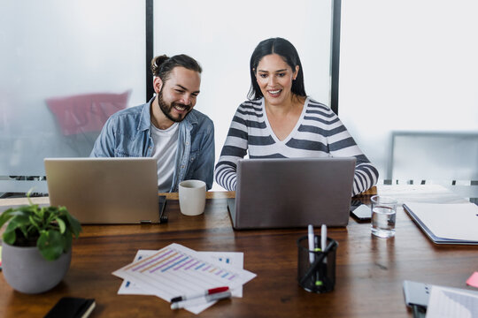 latin business couple young man and senior woman manager having a discussion and working in an office in Mexico Latin America, hispanic coworkers or teamwork using laptop or computer