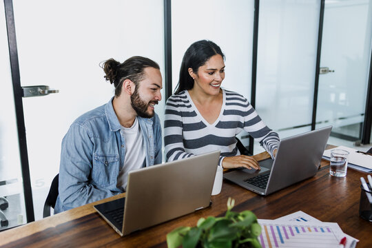latin business couple young man and senior woman manager having a discussion and working in an office in Mexico Latin America, hispanic coworkers or teamwork using laptop or computer