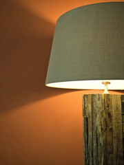 Cozy reading lamp with wooden base and grey lampshade against a red wall. Minimalist, tasteful home...