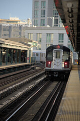 train arriving on platform in court square queens long island city new york nyc famous outdoor elevated station stop seven 7 metro commuter line tall buildings in background tracks railroad track