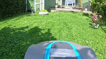 A robotic lawn mower cutting green lawn during a sunny day. The machine is scheduled to automatically cut daily and efficiently trims and maintains backyards	