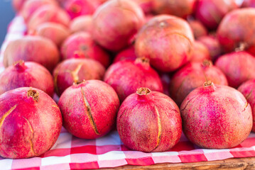 A close-up of a a vibrant red pomegranate from a neatly arranged fruit display at an outdoor...