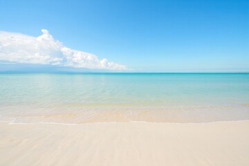 Fototapeta premium A serene view of a calm turquoise ocean meeting a sandy beach under a bright blue sky with fluffy clouds