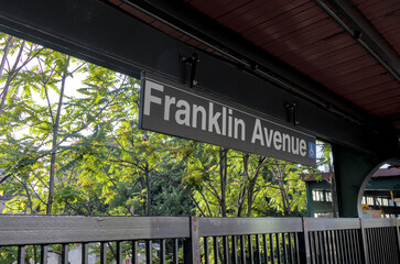franklin avenue subway train station stop sign on shuttle platform with trees in the background (elevated outdoor above ground metro commuter stop) crown heights brooklyn new york city