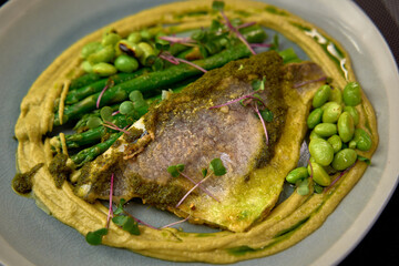 A Culinary Delight Featuring Pan-Seared Fish Surrounded by Fresh Vegetables and a Vibrant Green Sauce Served on a Modern Plate