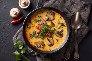 A bowl of soup with mushrooms and a spoon on a table