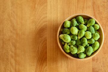 Top view of fresh organic brussels sprouts raw in a wooden bowl on a wooden table