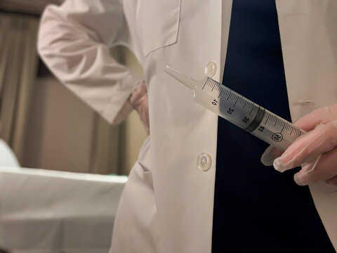Medical Professional Holding Large Syringe in Clinical Setting