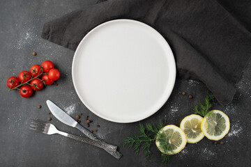 Empty white  craftmade ceramic plate with cutlery and linen serviette on brown stone board