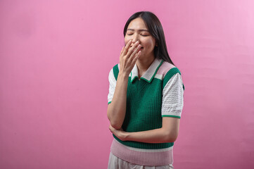 Asian woman looking up while smiling and pointing her index finger upward with an inspired expression, standing against a plain pink background