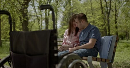 A loving couple shares a tender moment on a park bench, demonstrating profound support and connection despite disability. Their affection radiates a beautiful bond of understanding and care in nature.
