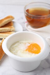 Half-boiled egg in bowl and toasted bread on white marble table, closeup. Traditional asian breakfast