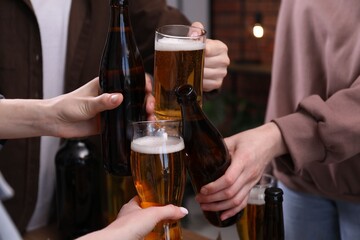 Friends clinking glasses of beer indoors, closeup