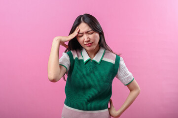 Asian woman closing her eyes tightly and touching her temple in pain, showing an expression of...