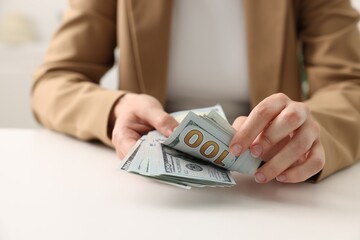Woman counting money at white table, closeup