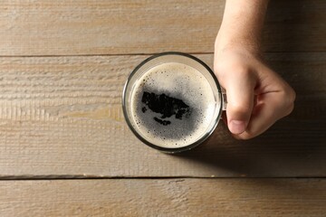 Man with glass mug of beer at wooden table, top view. Space for text