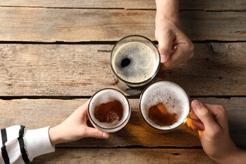 Friends with glasses of beer at wooden table, top view. Space for text