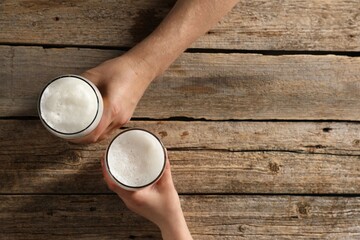 Friends with glasses of beer at wooden table, top view. Space for text