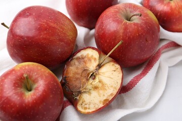 Spoiled apple and good ones on white table, closeup