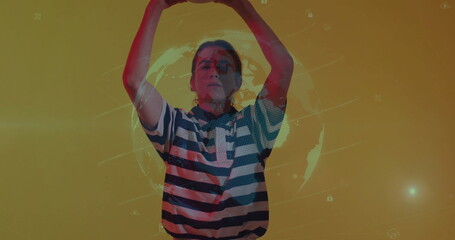 Raising arms above head creating curved shape at yellow backdrop, with holographic globe, UI icons