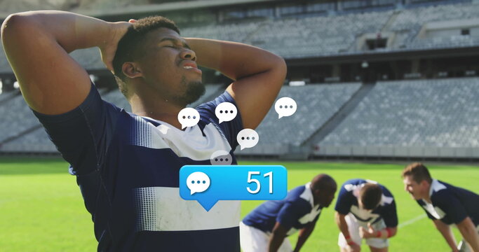 Holding head rugby player standing on stadium turf, chat bubbles, notification bubble, copy space - Powered by Adobe
