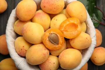 Fresh apricots in basket on wooden table, flat lay