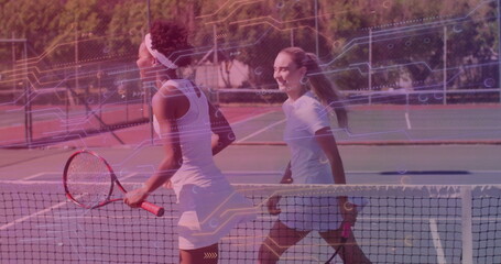 Meeting two female tennis players approaching each other at net on court, with rackets and fence