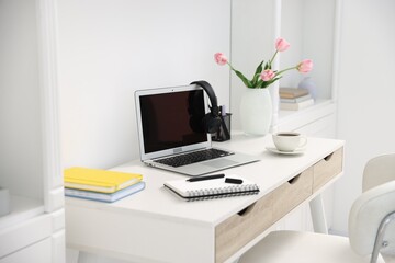 Desk with modern laptop, coffee and stationery in home office